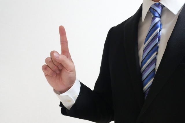 スーツを着た男性が人差し指を立てている